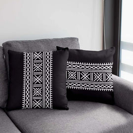 Black square and rectangular cushion covers with white geometric bands on a grey chair.