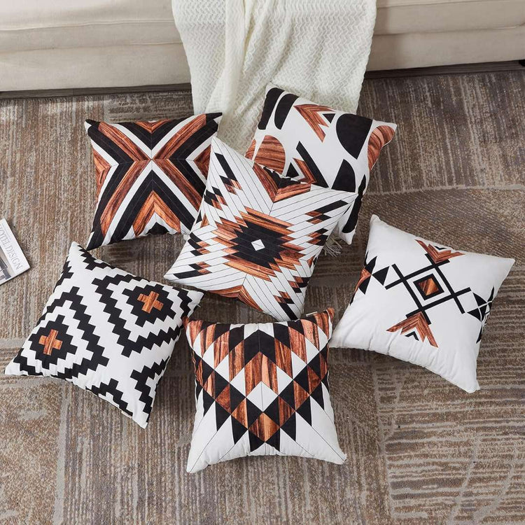 Rust, black and cream geometric cushion covers arranged in a fan on a wooden floor.