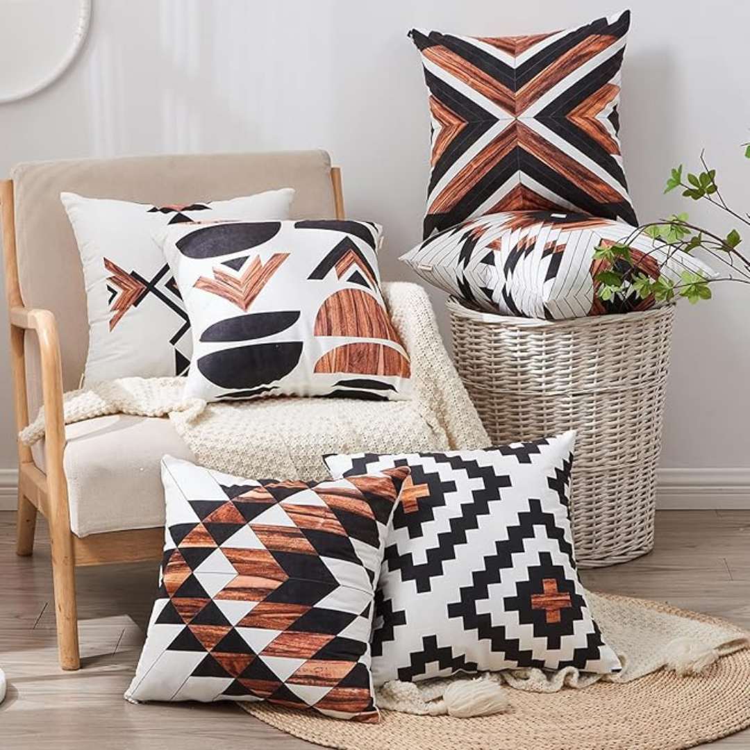 Rust, black and cream geometric cushion covers displayed on chairs and the floor.