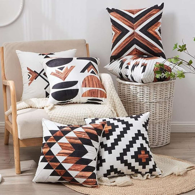 Rust, black and cream geometric cushion covers displayed on chairs and the floor.