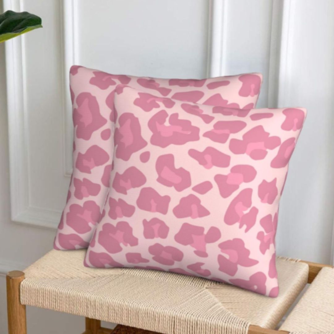 Two pink spotted cushion covers displayed on a wooden bench.