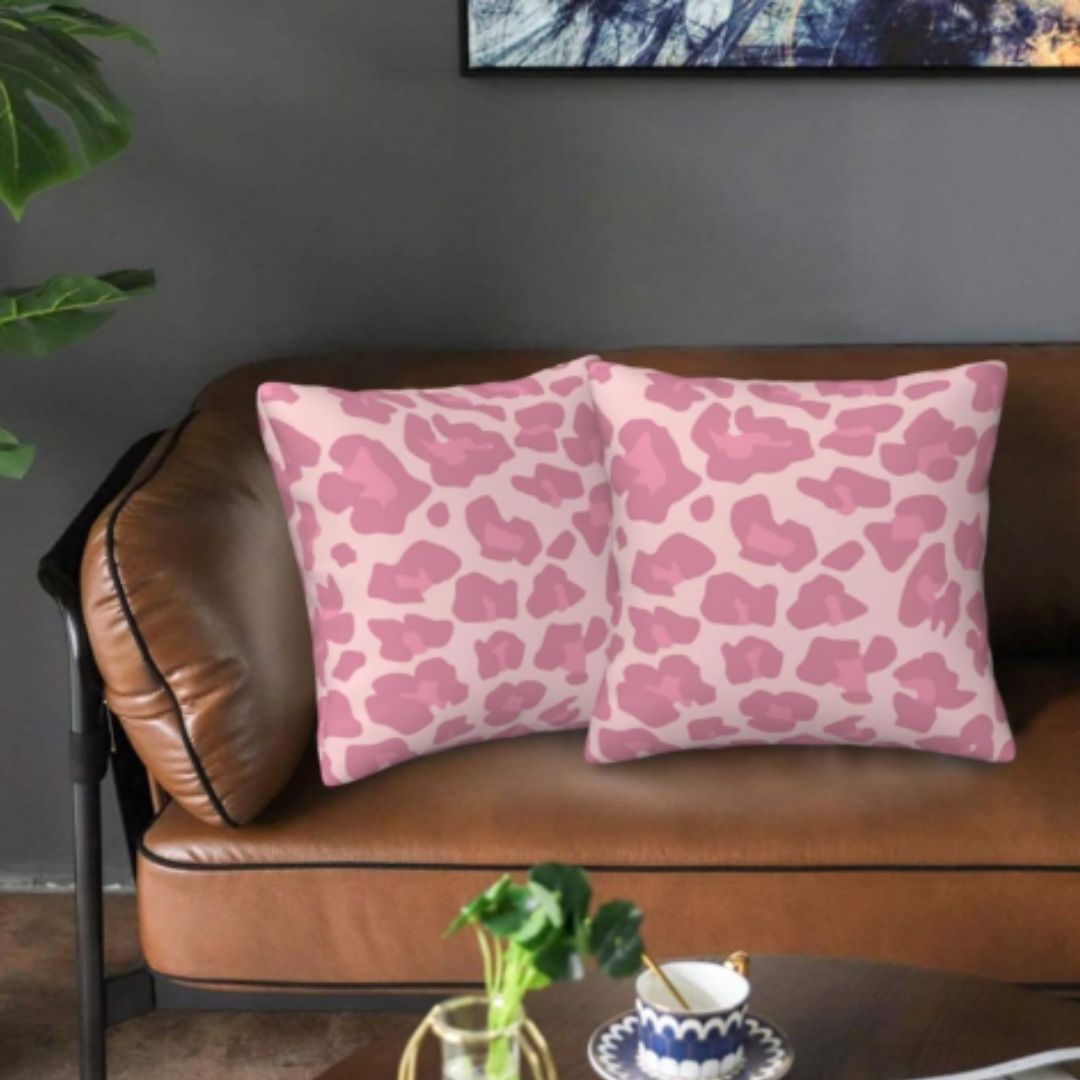 Two pink spotted cushion covers arranged on a brown leather sofa.