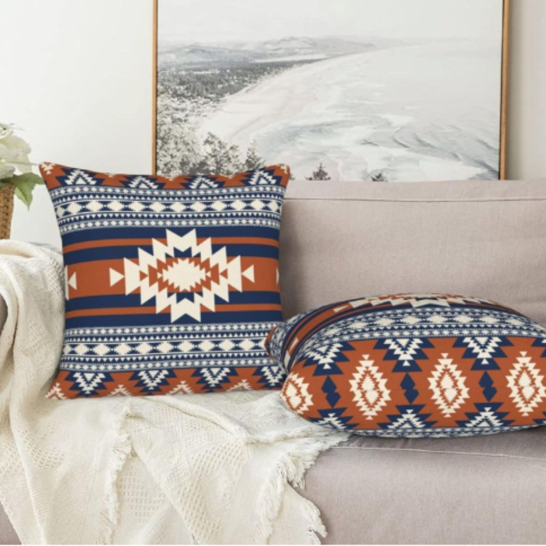 Navy, rust and cream geometric cushion covers arranged on a sofa.