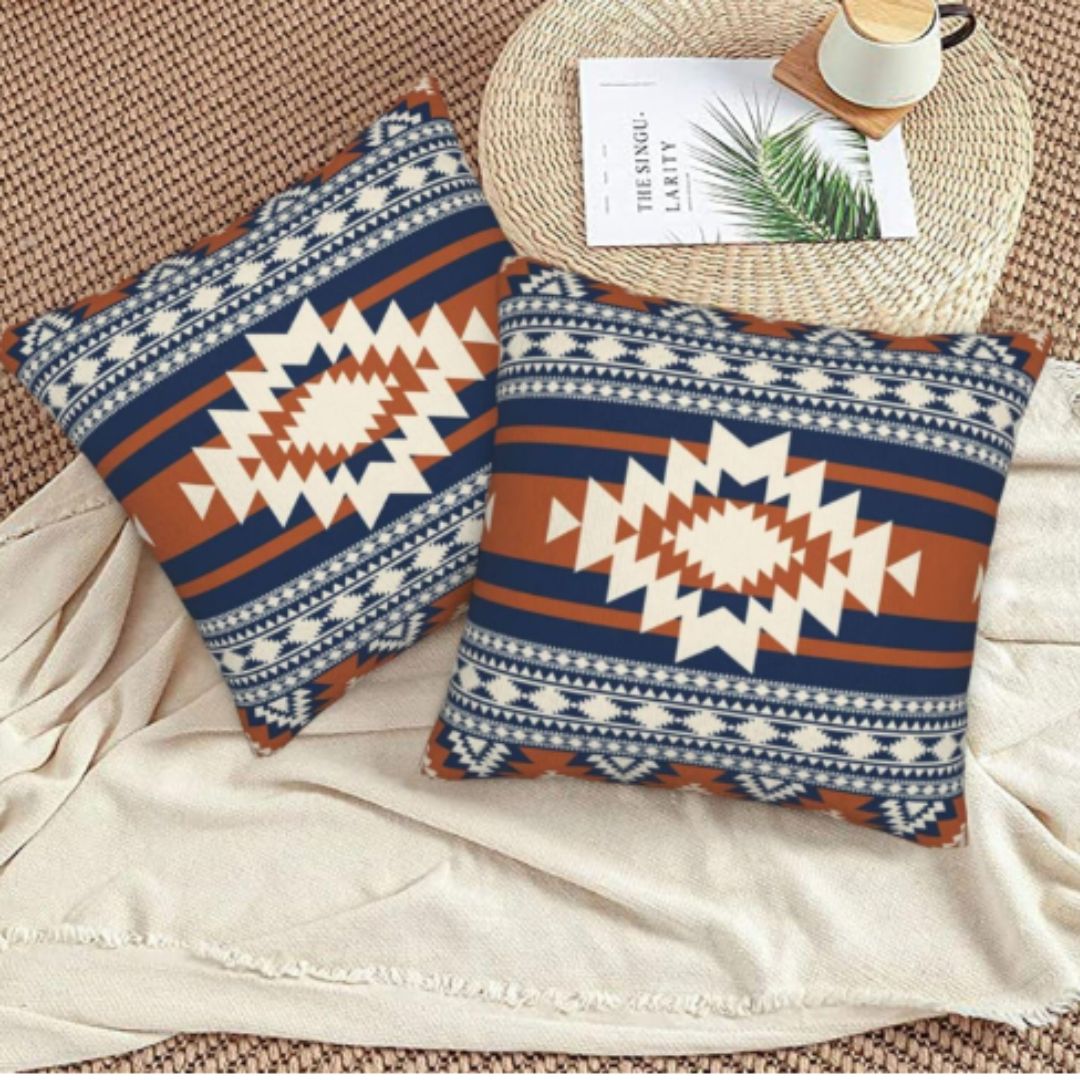 Two navy, rust and cream geometric cushion covers viewed from above.
