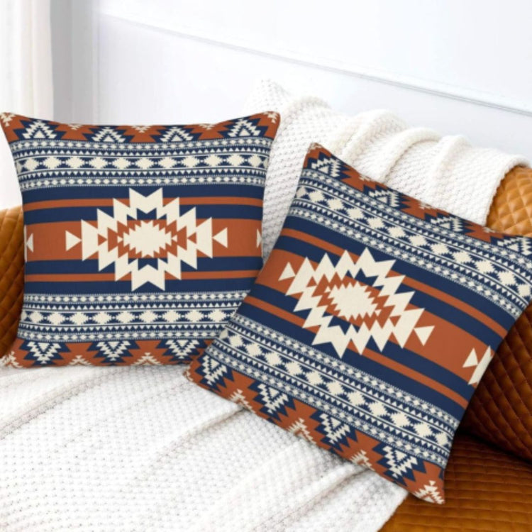 Two navy, rust and cream geometric cushion covers on a light textured sofa.