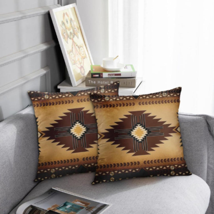Two ochre cushion covers with dark brown stepped diamonds and patterned borders on a grey sofa.