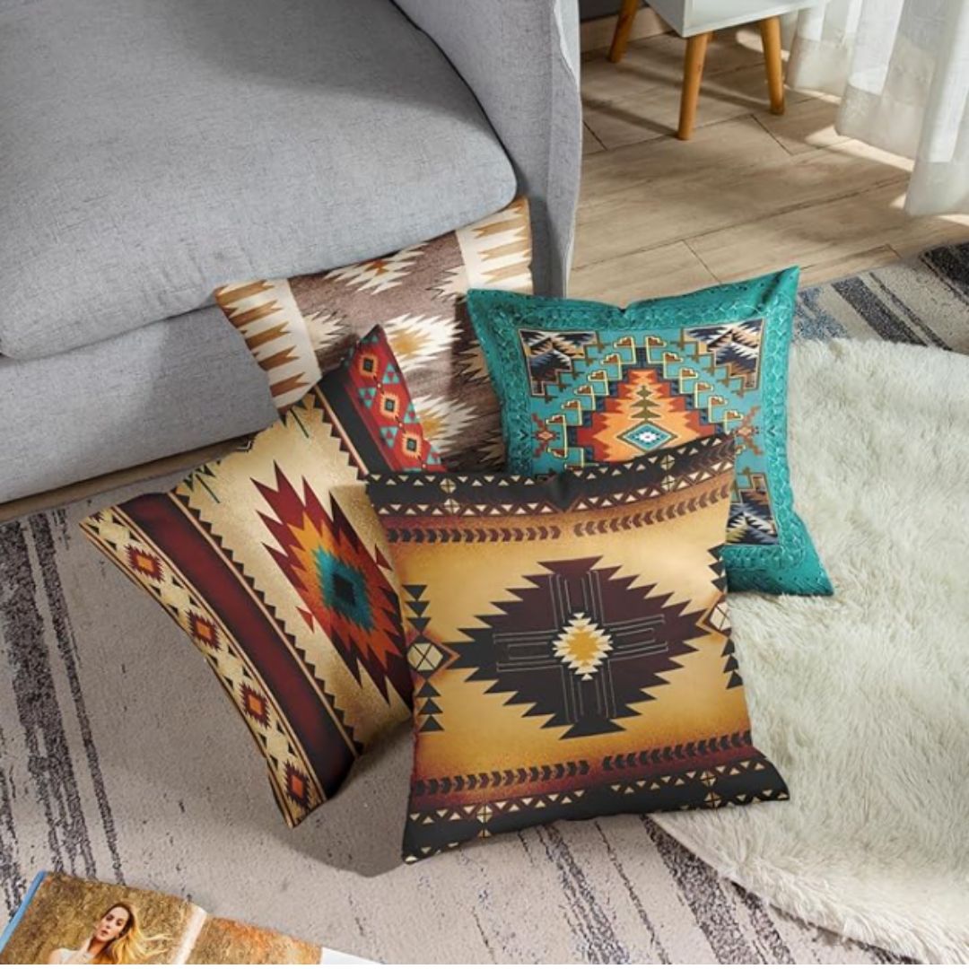 Four brown, cream and teal geometric cushion covers arranged together beside a sofa.