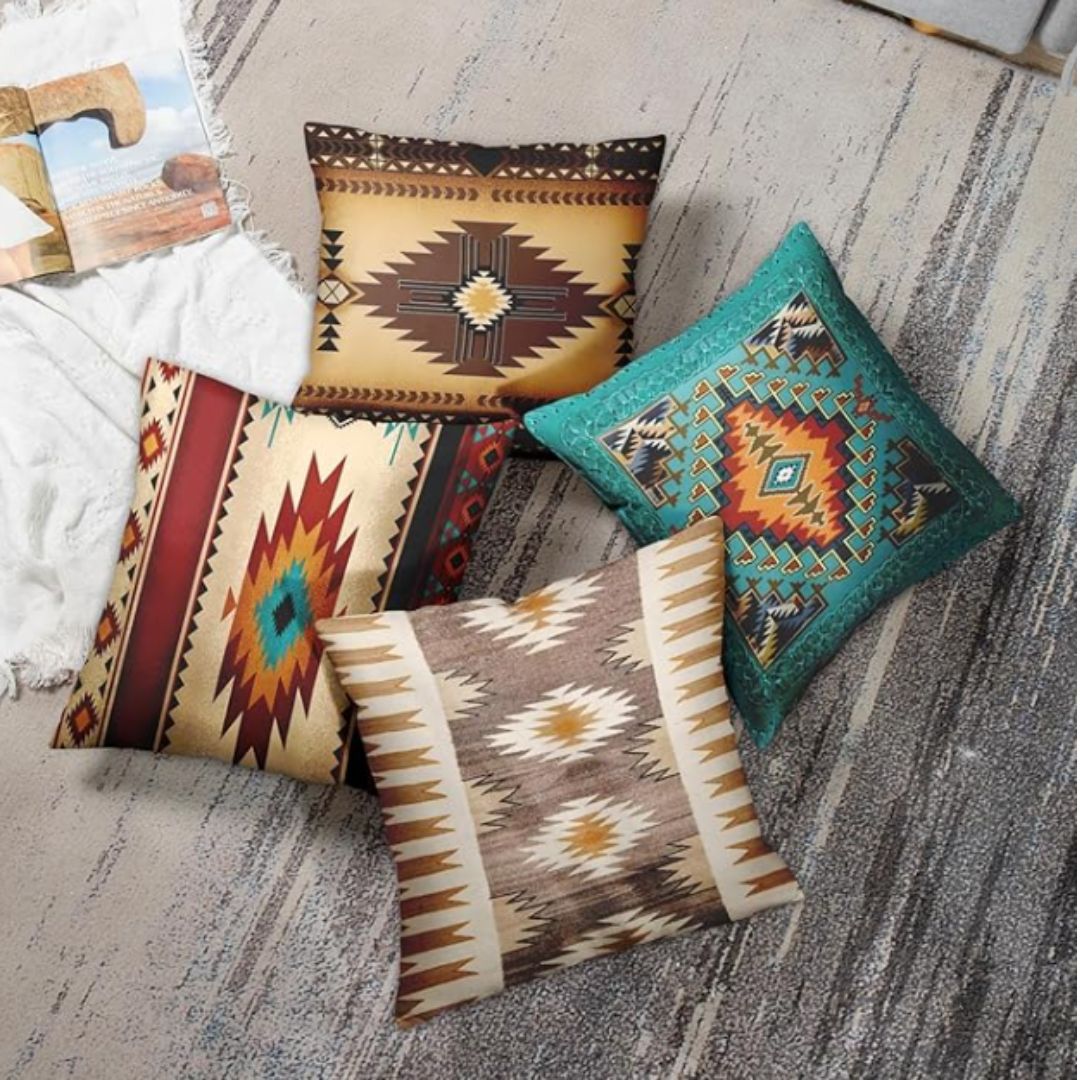 Four brown, cream and teal geometric cushion covers arranged together beside a sofa.