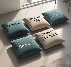 Five teal and cream cushion covers with short Dream and Be kind messages.