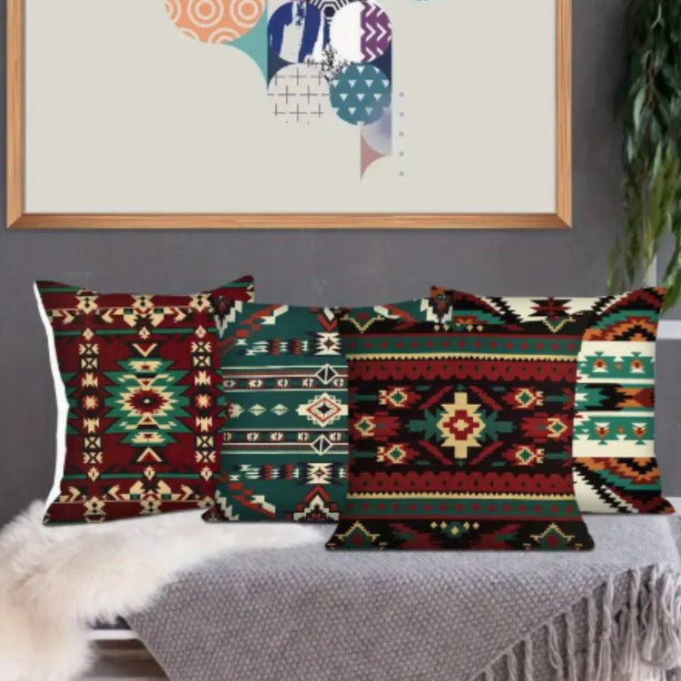 Four red, teal and cream geometric cushion covers displayed in a living room.
