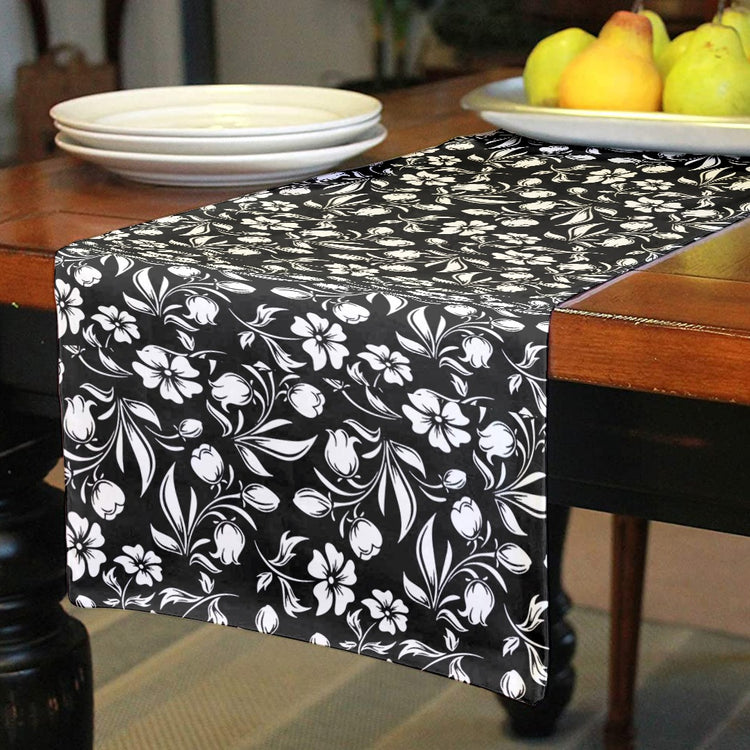 Black table runner with white flowers and leaves.