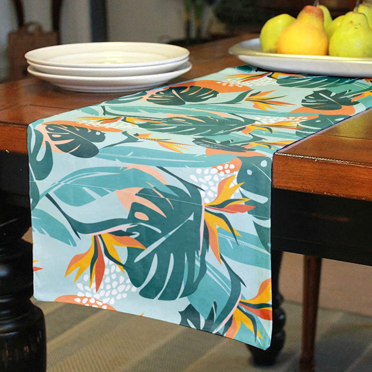 Table runner with teal tropical leaves and orange floral accents.