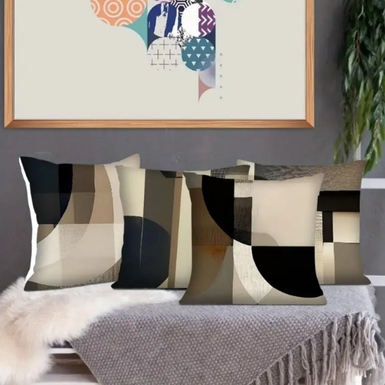 Four neutral geometric cushion covers with curved black, beige and gray panels on a light surface