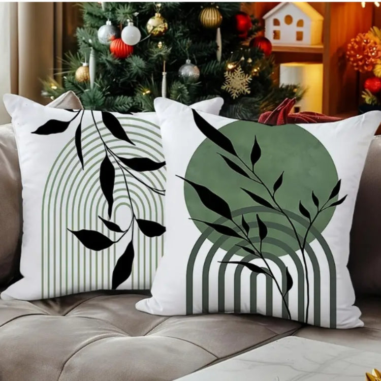 Two white cushion covers with black leafy stems, green shapes and fine vertical lines.