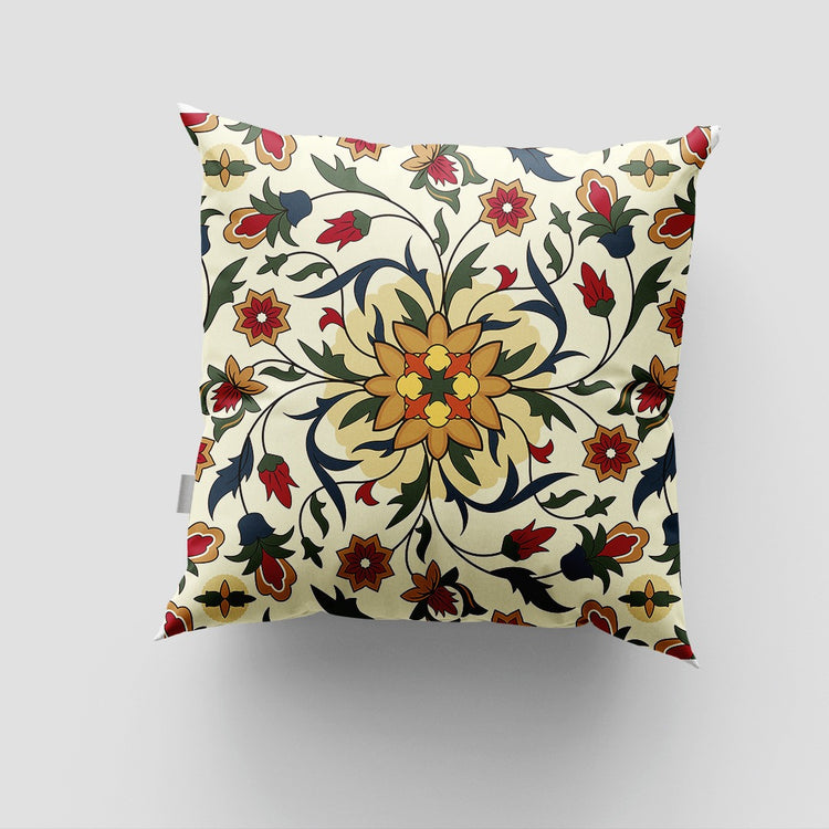 Cream cushion cover with an ornate yellow floral centre and curling green and red leaves.