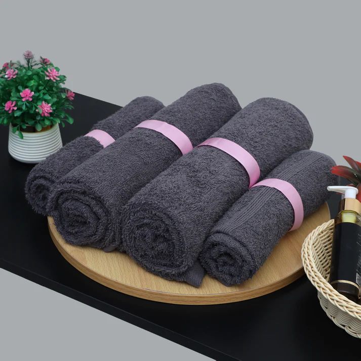Charcoal grey cotton towels rolled and arranged on a tray.