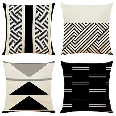 Four black and cream cushion covers with fine lines and bold geometric panels.