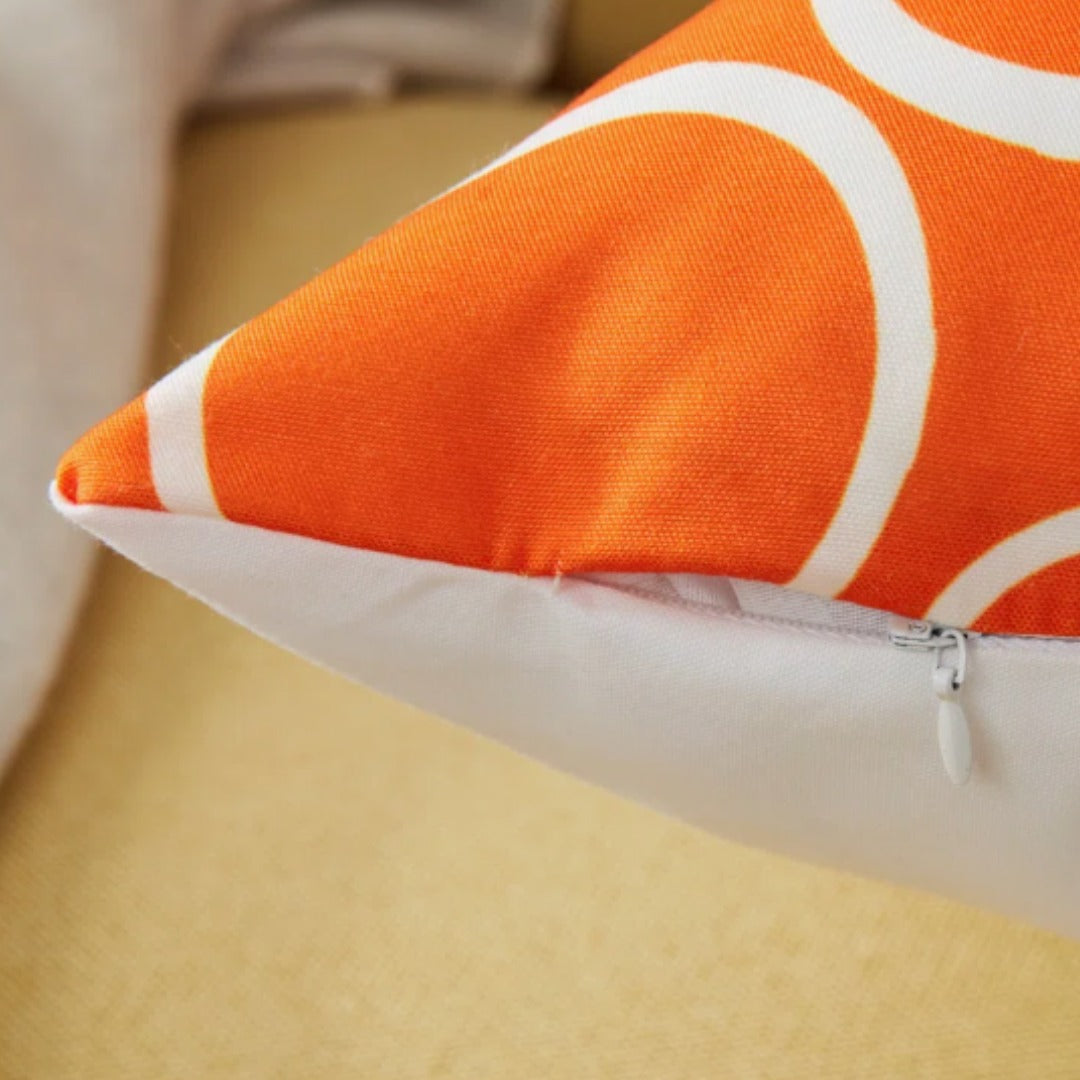 Close view of an orange and white circle-pattern cushion cover showing the zip seam.