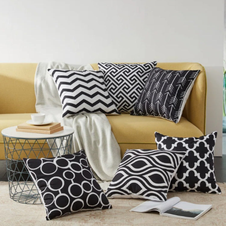 Black and white geometric cushion covers displayed on a mustard sofa and rug.