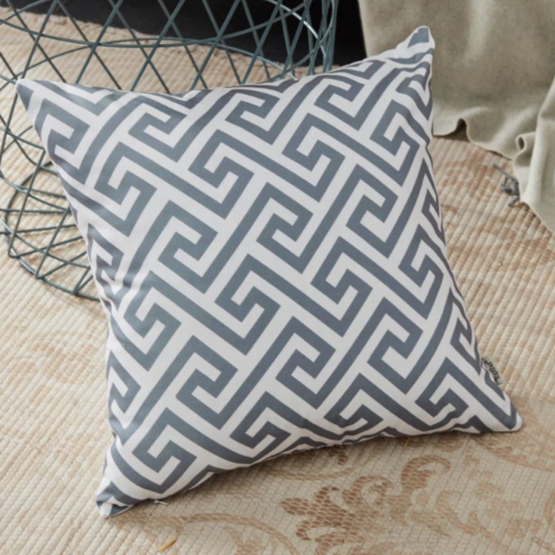 Grey and white cushion cover with an angular maze-like geometric pattern.