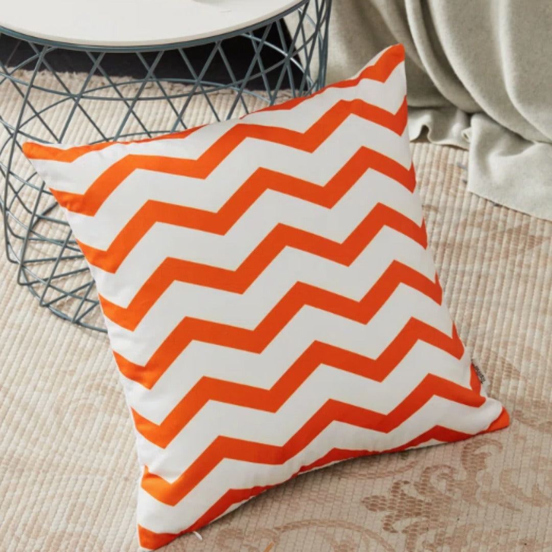 White cushion cover with bold orange zigzag stripes.