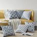 Grey and white geometric cushion covers displayed on a mustard sofa and rug.