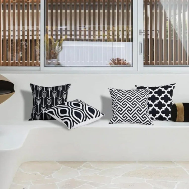 Black and white geometric cushion covers arranged on a white sofa.