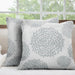 Two white cushion covers with pale grey circular floral patterns on a sofa.