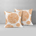 Two white cushion covers with orange circular floral patterns.