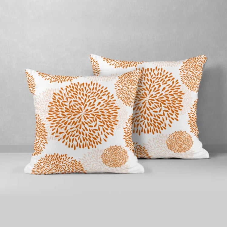 Two white cushion covers with orange circular floral patterns.