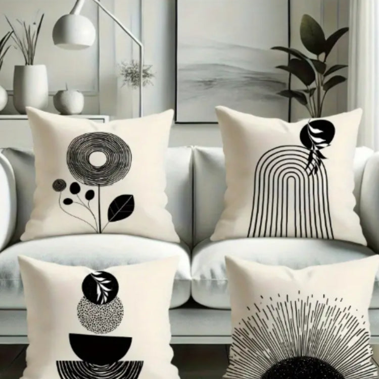 Four cream cushion covers with black abstract flowers, arches and semicircles on a sofa.