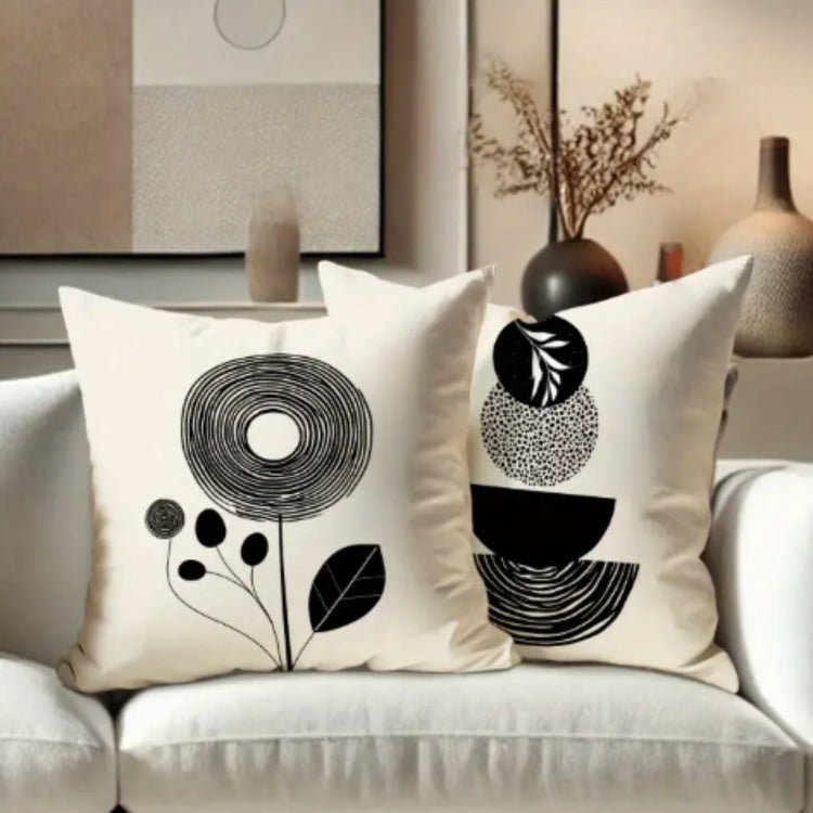 Four cream cushion covers with black abstract flowers, arches and semicircles on a sofa.
