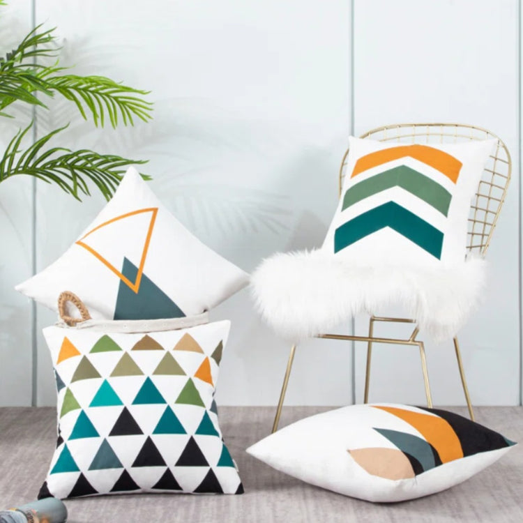 Teal, mustard and grey geometric cushion covers displayed on white chairs.