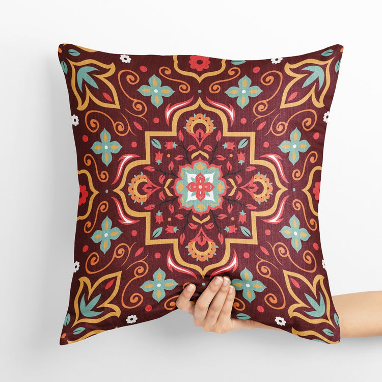 Burgundy cushion cover with a large ornate gold coloured and teal floral medallion.