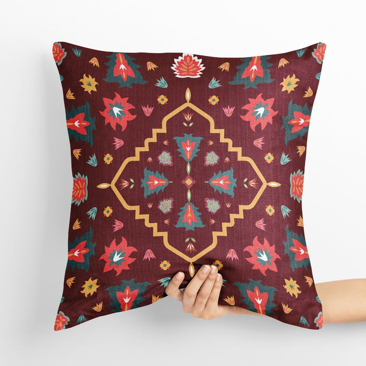 Burgundy cushion cover with a geometric floral medallion and scattered colourful motifs.