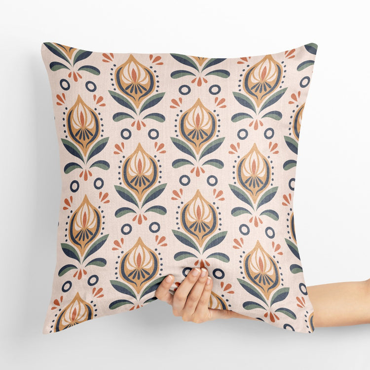 Cream cushion cover with repeating peach, grey and gold coloured botanical motifs.