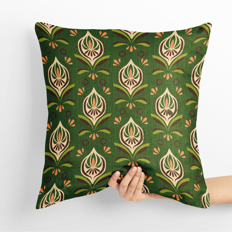 Green cushion cover with repeating gold coloured and cream botanical motifs.