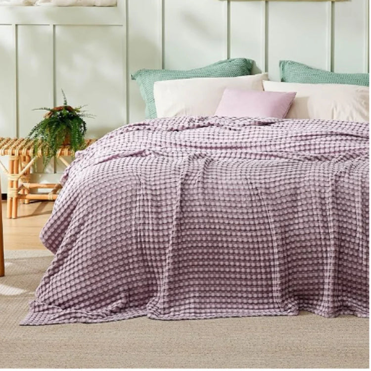 Lilac waffle-weave blanket spread across a bed.
