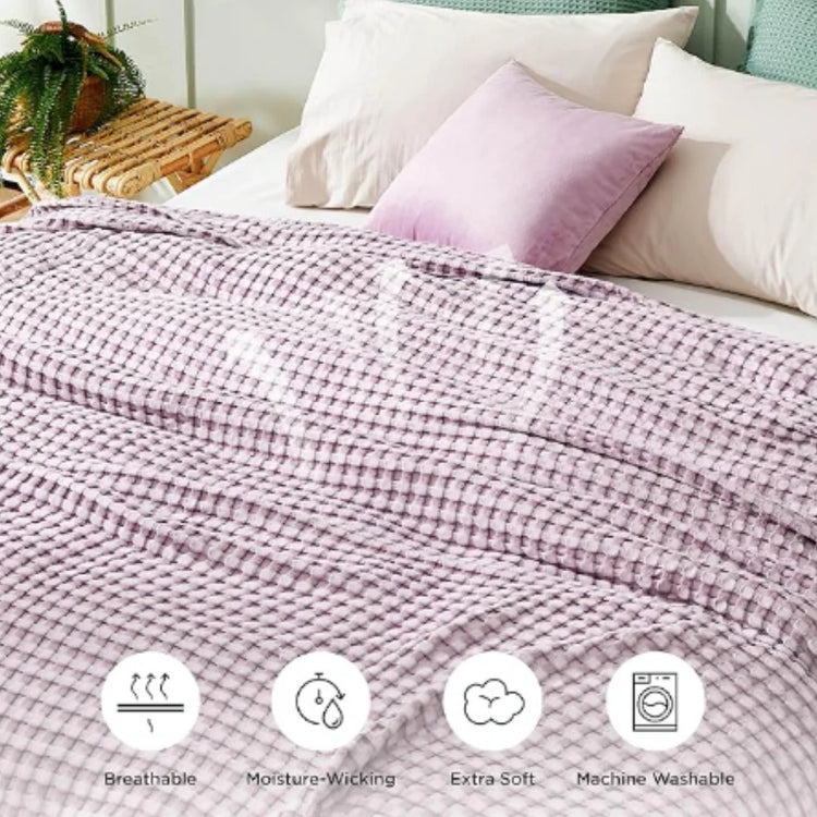 Lilac waffle-weave blanket on a bed with product-care symbols below.