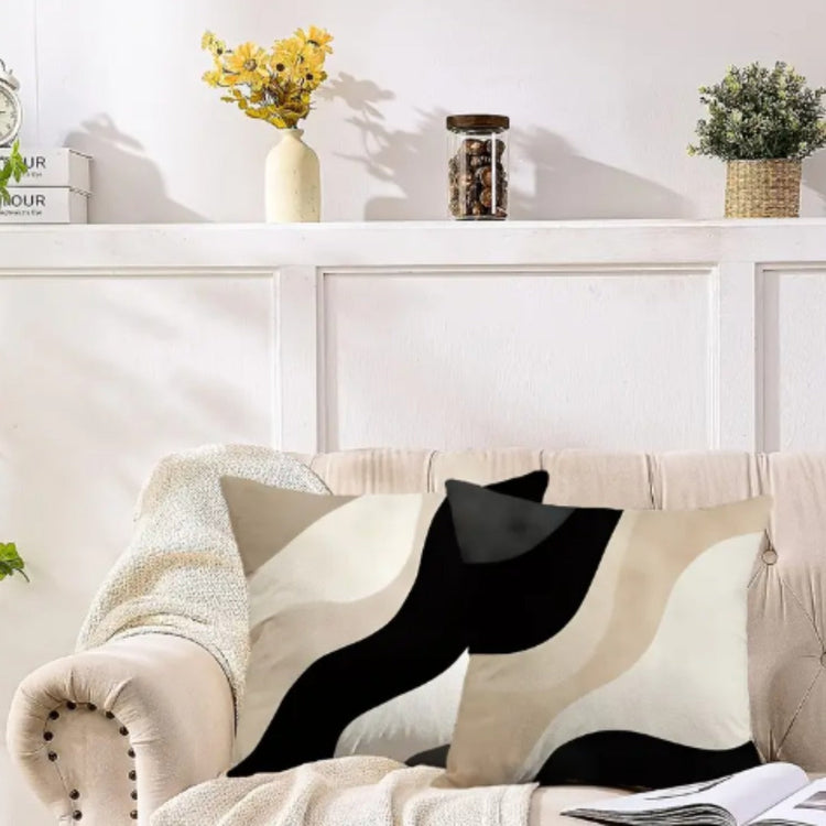 Black, beige and cream abstract cushion covers with sweeping curved panels on a sofa.