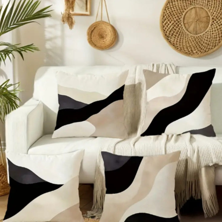 Black, beige and cream abstract cushion covers with sweeping curved panels on a sofa.