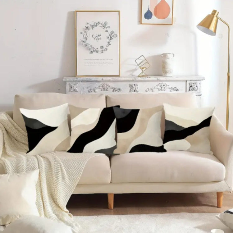 Black, beige and cream abstract cushion covers with sweeping curved panels on a sofa.