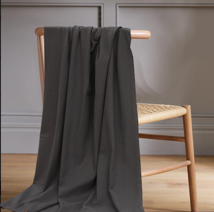 Charcoal grey throw draped over a wooden chair.