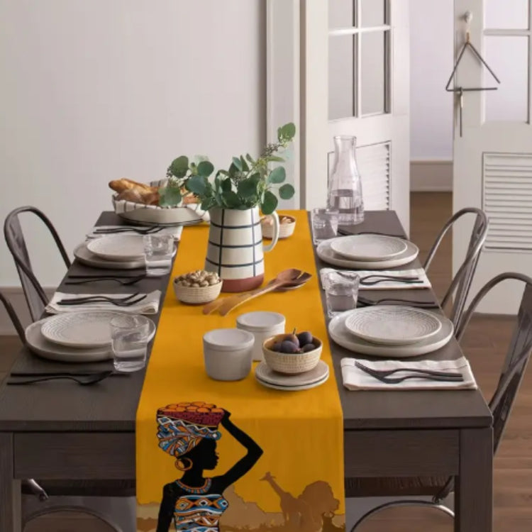 Yellow table runner with a headwrap portrait on a set dining table.