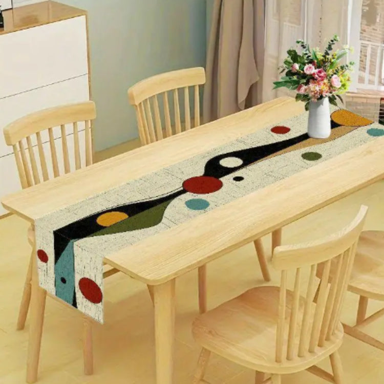 Cream table runner with abstract black, teal and red geometric shapes.