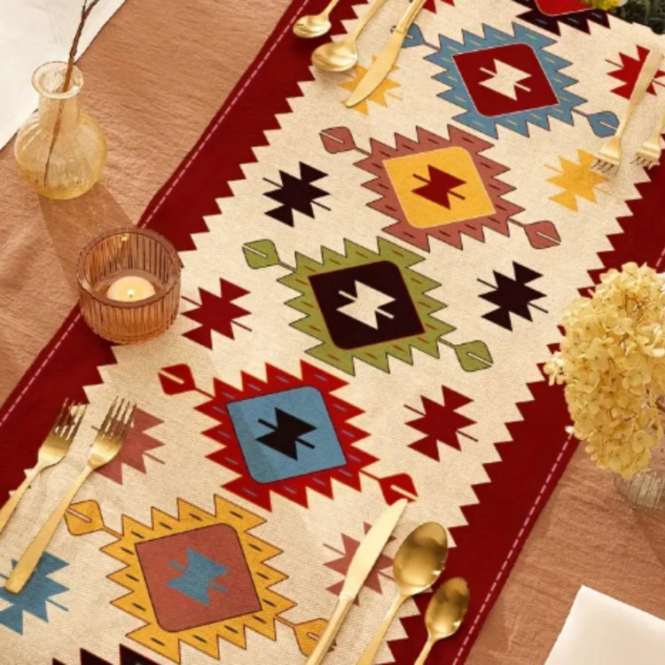 Close view of colourful geometric diamonds on a cream table runner with red borders.