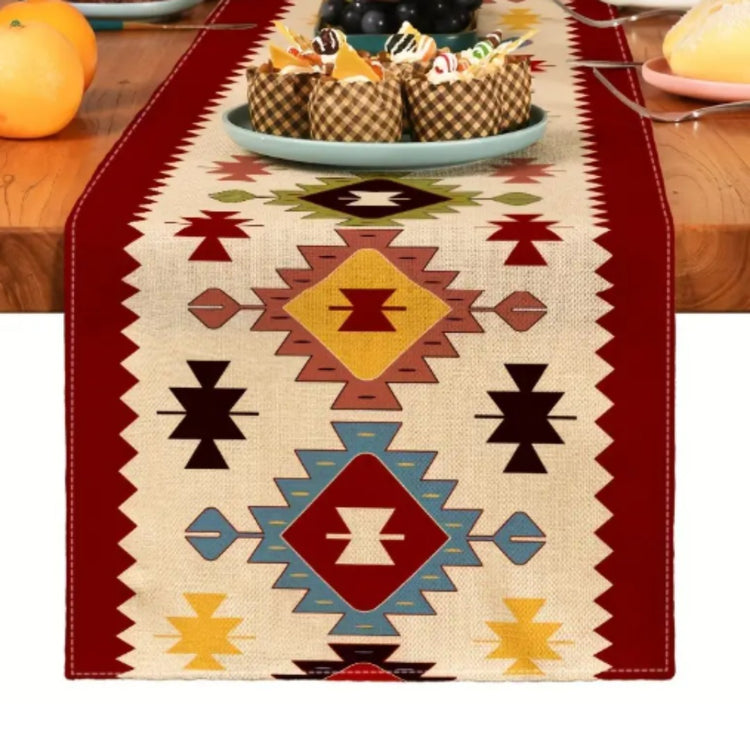 Close view of colourful geometric diamonds on a cream table runner with red borders.