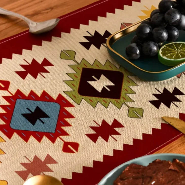 Close view of colourful geometric diamonds on a cream table runner with red borders.
