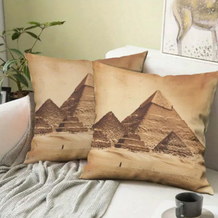 Two beige cushion covers with pyramid illustrations arranged on a sofa.