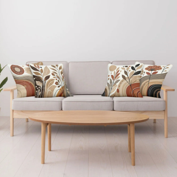 Earthy botanical cushion covers arranged on a pale sofa behind a wooden coffee table.